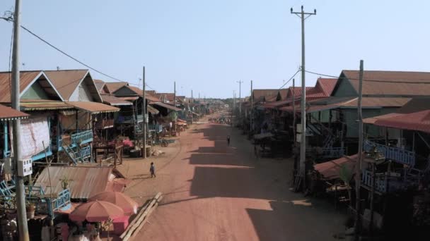 Жилые дома на деревянных столбах и красной грунтовой дороге в Плавучей деревне Кампонг Плук в Камбодже возле беспилотника Tonle Sap Lake, рейс 4k — стоковое видео