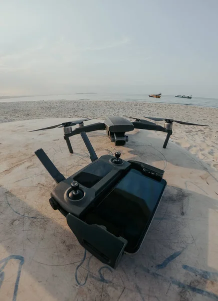 Telecomando drone e drone grigio e telefono cellulare su un tavolo sulla spiaggia all'alba — Foto Stock