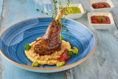 Ahşap masadaki patates püresinin üzerinde ağır ateşte pişmiş kuzu incik.