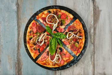 Ahşap arka planda üstten bakıldığında üstün karışık pizza..