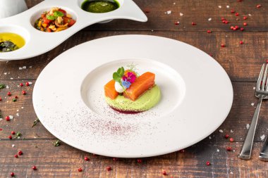 Yeşil püre ve yenilebilir çiçekli gurme somon filetosu.