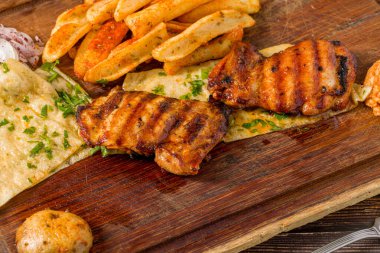 Kızartma, lavaş, soğan ve bulgur ile servis edilen kemiksiz ızgara tavuk pirzolası.