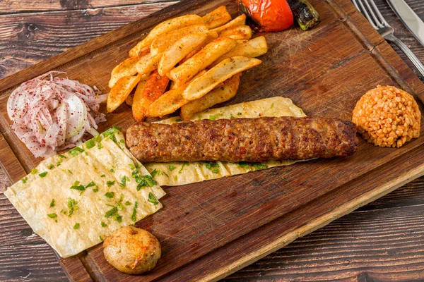 Geleneksel Adana kebabı patates, lavaş, bulguru ve soğan salatası.