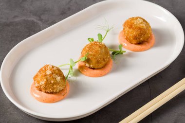 Baharatlı soslu ve yeşillikli üç kızarmış tavuk köftesi.