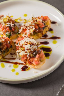 Domates, peynir, fesleğen ve balzamik çiselemeli gevrek bruschetta.