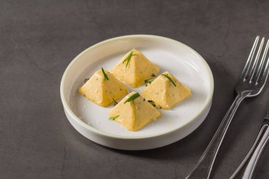 Dört piramit biçimli bitkisel peynir, soğanla servis edilir.