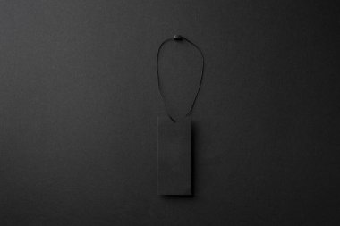 Minimalist siyah karton elbise etiketi ile koyu arkaplanda ip
