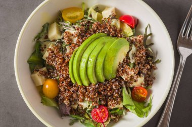 Taze kinoa salatası, avokado, vişneli domates ve karışık yeşillikler.