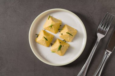 Dört piramit biçimli bitkisel peynir, soğanla servis edilir.