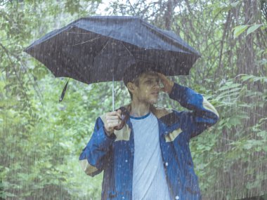 şiddetli yağmur sırasında tropikal yağmur ormanlarında şemsiye ile zarif yakışıklı sakallı adam portresi