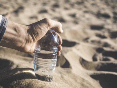 El alarak şişelenmiş içme suyu kum plaj