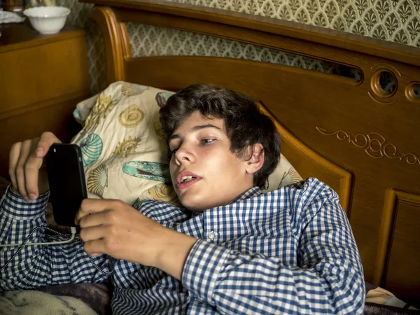 Młody Nastolatek Chłopiec Leżąc Relaksujący Łóżku Telefonem — Zdjęcie stockowe