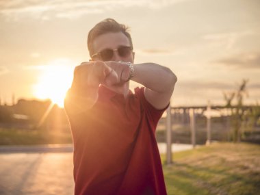 Dışarıda genç hipster kamerada günbatımı sırasında işaret sokak