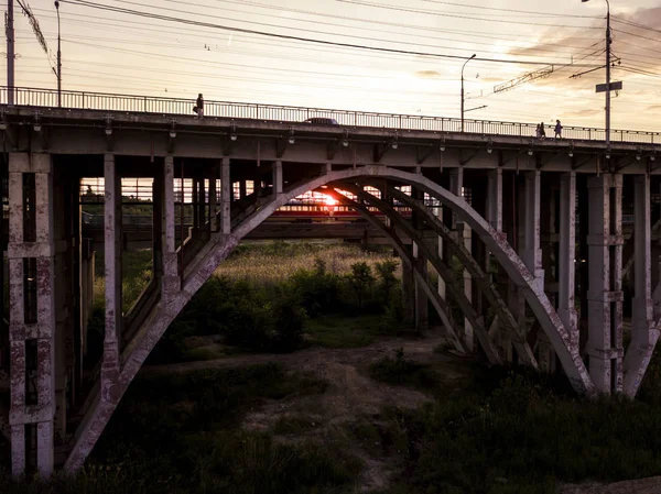 橋のアーチの下に行く電気軌道部門の責任トーのシルエット — ストック写真