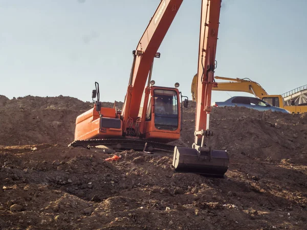 excavator with bucket making earth embankments and digging dusty ground