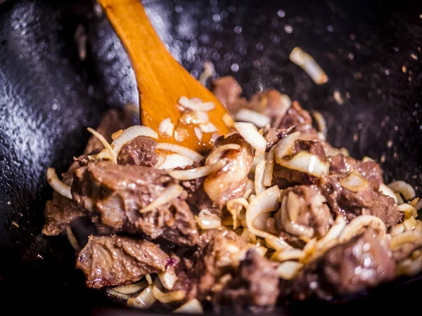 close up wooden stick mixing the meat stew with vegetables with dark background