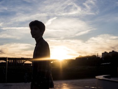 Genç adam şehrin sokak ve gün batımının ayakta silüeti onun arkasında olduğunu