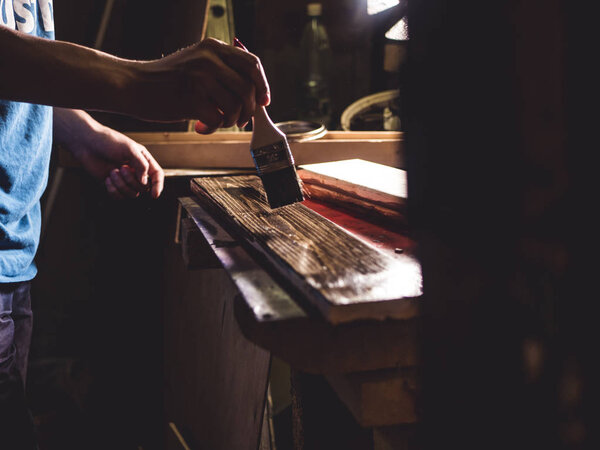 close up painter worker crafting the wooden things in dark workshop