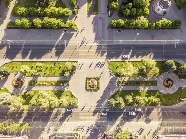 aerial overhead view of main street in the city with traffic and green trees