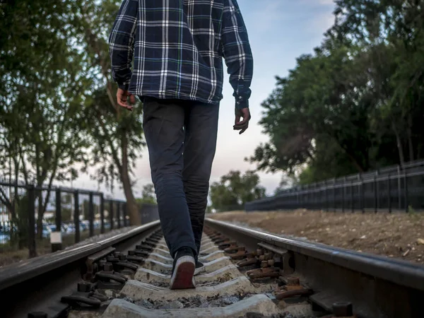 back of  lonely man walking far away on the railway track