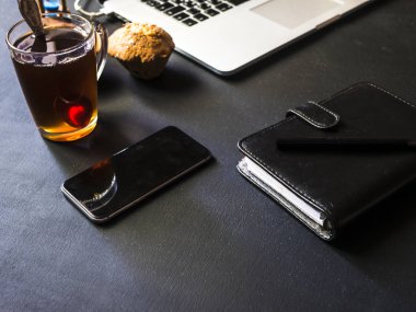 karanlık Ofis masaları ile dizüstü çay kek telefon ve dizüstü kapatın