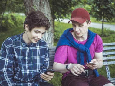 telefonları haberlerde kaydırma ve fotoğraf kontrol gülümseyen iki genç adam