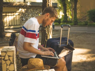 şehir içinde çuval Bagaj ile Laptop çalışma yaz rahat kıyafetler içinde sakallı genç adam