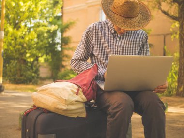 yaz şapka bagaj bavul ile laptop sokakta oturan genç adam