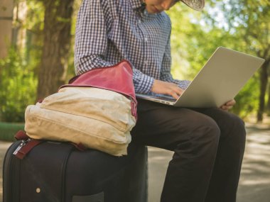 dizüstü bilgisayarda çalışan sokakta büyük bavul kişi oturup kapatın 