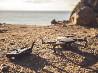 deniz güneş ışığı ile tonlu arka plan üzerinde dağ yeryüzünde döşeme dron ve denetleyicisi oyun çubuğu yukarı kapatın