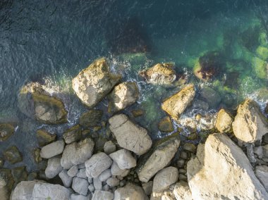 Deniz doğrudan yukarıdaki görünümü Sahili dalgalar ve büyük taşlar bir yaz gününde