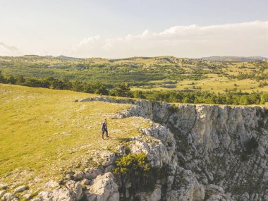 Hava geniş açı panorama görünümünü dağ kenar cliff üzerinde yürüyen adam 