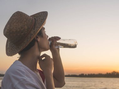 Genç çocuk bir gün batımı sahilde duran su şişe