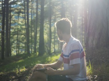 güneşli bir günde orman ve not defterinde yazılı şiir rahat oturan genç handscome adam zemin
