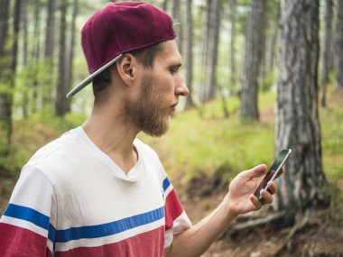 Genç sakallı hippi blogger olun canlı akışı sosyal ağ ormanda yürüyüş