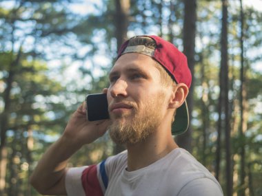 Doğa frest Avrupa İsviçre'deki yürüyüş telefonla konuşurken şapkalı Genç sakallı hippi portresi kapatın