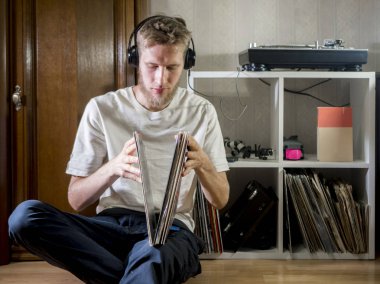 Genç adam, evde döner gramofon üzerinde sonraki oynamak için vinil kaydı seçin