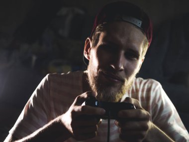 Genç sakallı adam yakın çekim video oyun denetleyicisi oyun çubuğu gamepad karanlık odada tutarak oyun oynarken portre