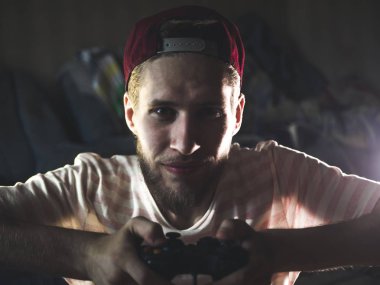 Genç sakallı adam yakın çekim video oyun denetleyicisi oyun çubuğu gamepad karanlık odada tutarak oyun oynarken portre
