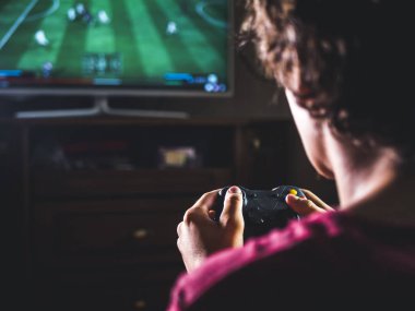 Genç adam için büyük ekranda spor simülatörü video oyun oynarken konsol oyun çubuğu denetleyicisiyle kapatın