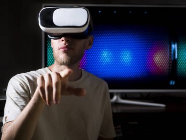 sanal gerçeklik gözlük evde karanlık odada kullanan genç yakışıklı sakallı adam portresi