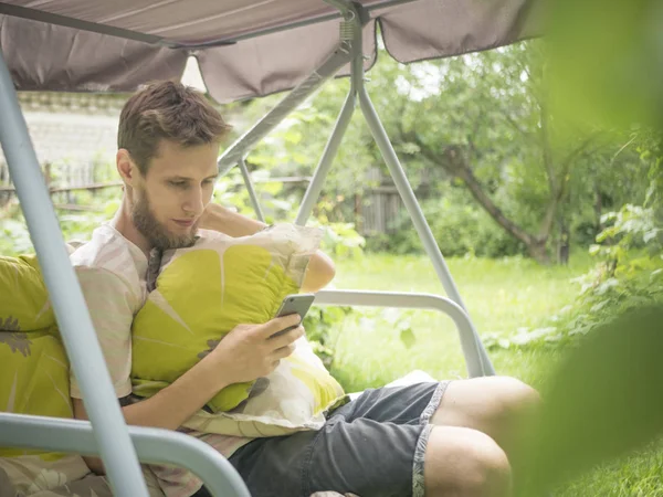 Junger Bärtiger Mann Sitzt Einem Sommertag Auf Der Gartenschaukel Couch — Stockfoto