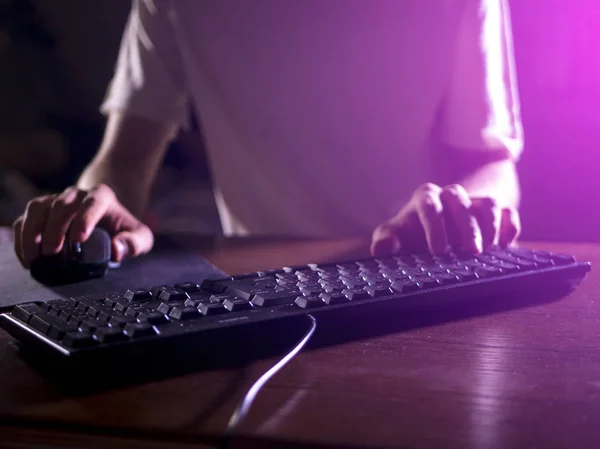 close up gamer hands on the keyboard playing video games in the night