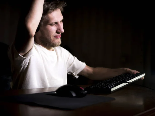 young mad crazy gamer breaking the keyboard playing video games on computer late in the night