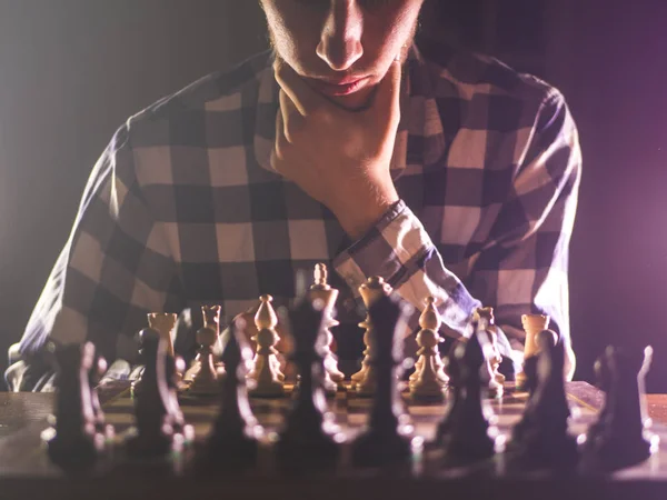 young unrecognizable male person thinking near the chess board concept with dark background