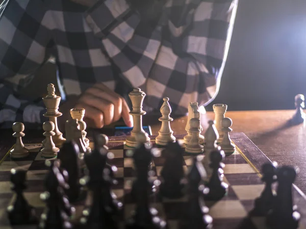 young bearded chess player playing a game on a tournament with dark background