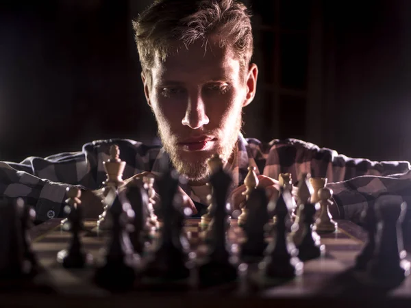 年轻的大胡子象棋大师坐在黑暗的房间里的下一个移动思考 — 图库照片