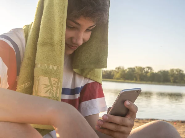 Nahaufnahme Teenager mit Handtuch auf dem Kopf in lässiger Kleidung mit Handy — Stockfoto