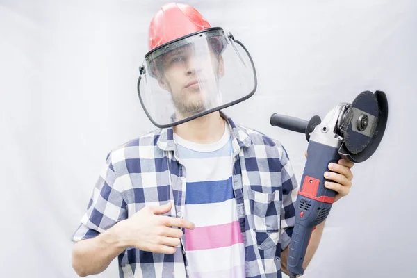 Joven trabajador casual masculino en máscara de vidrio protector con una máquina amoladora aislada n —  Fotos de Stock