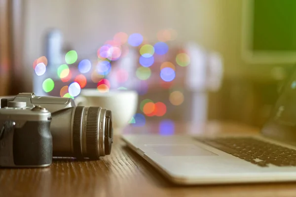 Cerca de la cámara en la mesa del lugar de trabajo del fotógrafo con el ordenador portátil f — Foto de Stock